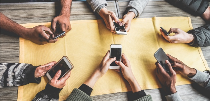 6 people holding cell phones around a table