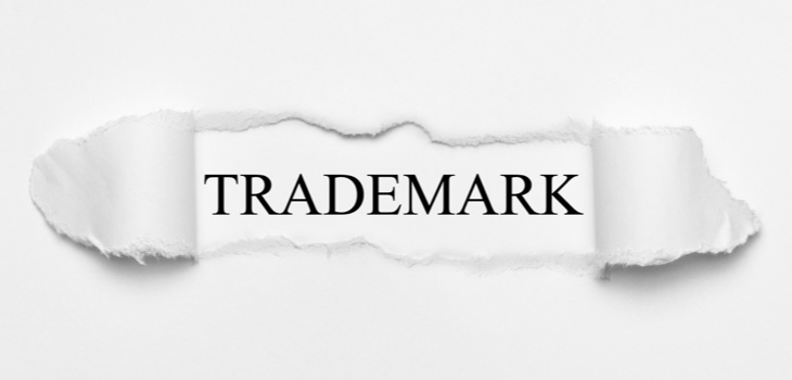 The word trademark being revealed from behind a ripped sheet of paper