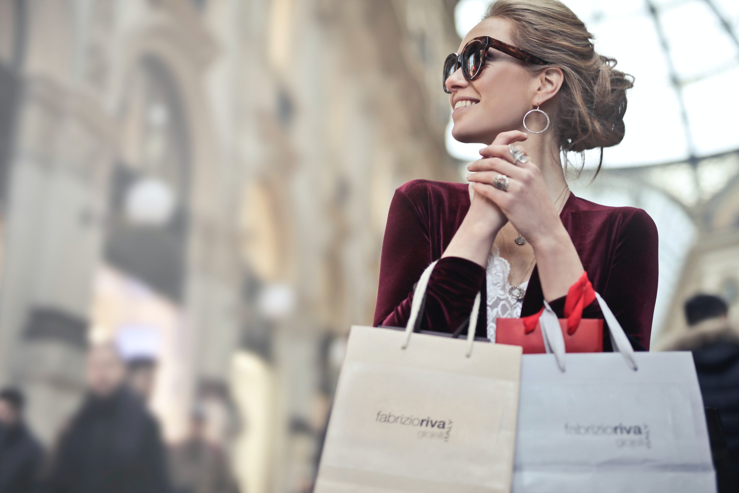 Woman in sunglasses holding shopping bags outside